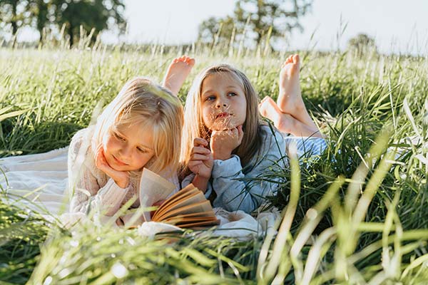 Enfants lisant dans l'herbe verte au camping Parc de Bellevue à Arvert en été