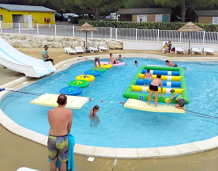 Enfants jouant sur un parcours Aqua Track dans la piscine du camping Parc de Bellevue à Arvert