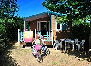 Children riding bicycles in front of a chalet for rent at the Parc de Bellevue campsite near La Palmyre