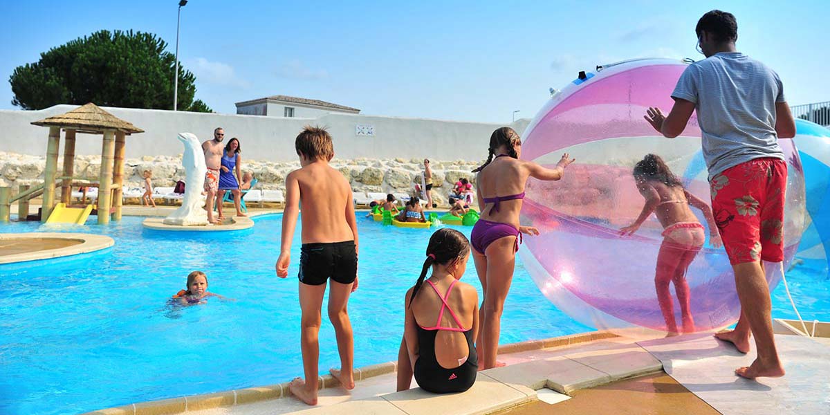 Enfants jouant au waterball dans la piscine du camping à Arvert