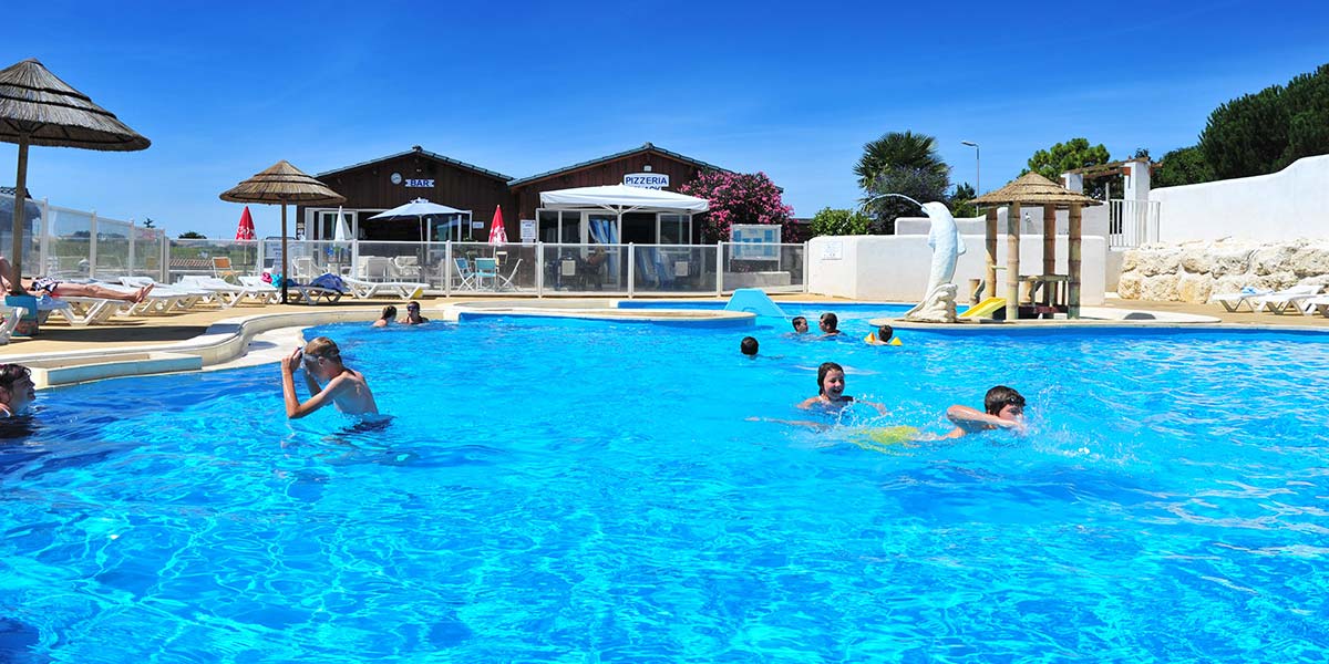 Piscine et plage avec parasol au camping Parc de Bellevue (17)